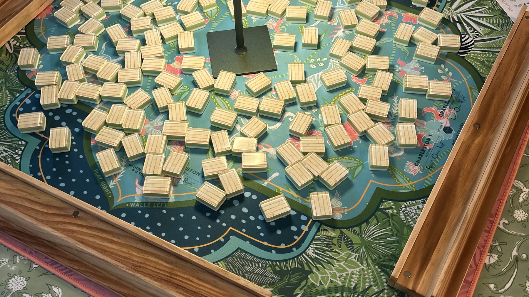 A mahjong table set for play, tiles face down and racks ready